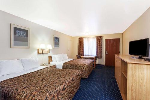 a hotel room with two beds and a flat screen tv at Days Inn by Wyndham Anaheim West in Anaheim