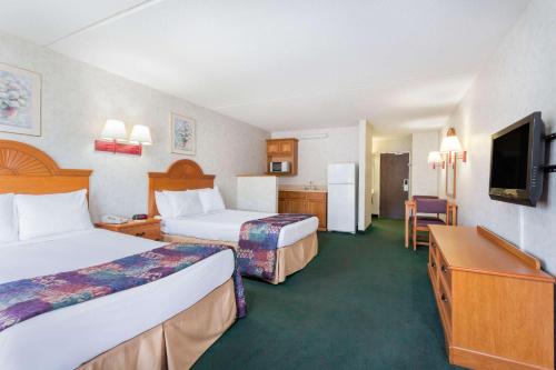 a hotel room with two beds and a flat screen tv at Days Inn & Suites by Wyndham Lexington in Lexington