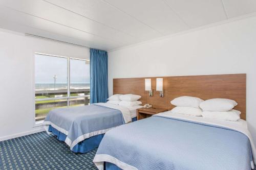 a hotel room with two beds and a window at Mariner Inn And Suites in Kill Devil Hills