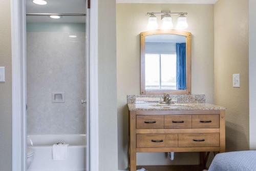 a bathroom with a sink and a mirror and a tub at Mariner Inn And Suites in Kill Devil Hills