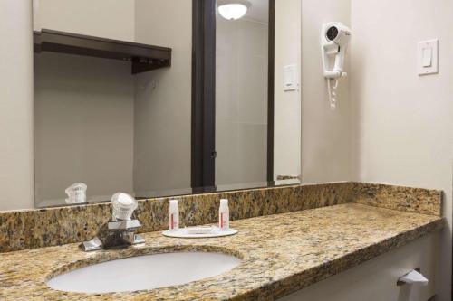 La salle de bains est pourvue d'un lavabo et d'un grand miroir. dans l'établissement Days Inn by Wyndham Montreal Airport Conference Centre, à Dorval