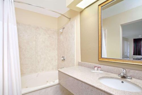 a bathroom with a sink and a mirror and a tub at Days Inn by Wyndham Kerrville in Kerrville