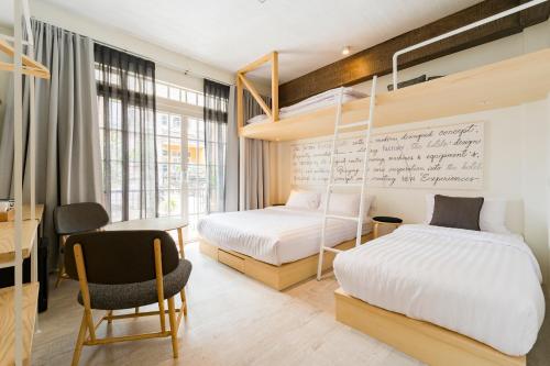 a bedroom with two beds and a desk and a chair at The Pattern Boutique Hotel in Bangkok