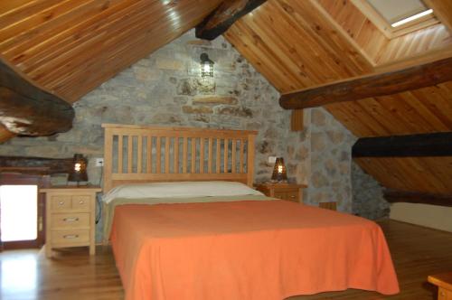 a bedroom with a bed and a stone wall at Casa Juez in Ascaso