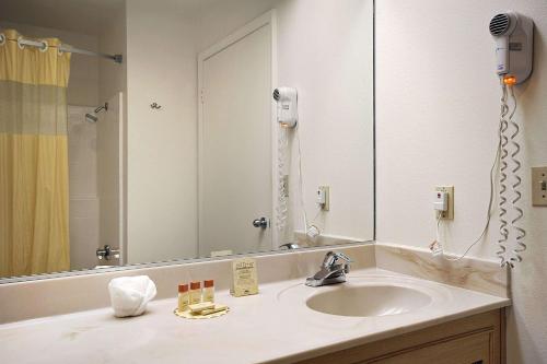 uma casa de banho com um lavatório e um espelho grande em Days Inn by Wyndham Riverside Tyler Mall em Riverside