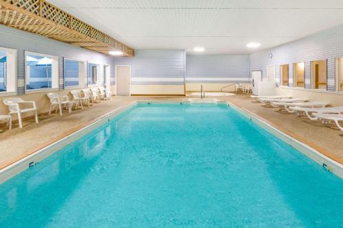 a swimming pool with blue water in a building at Days Inn by Wyndham Alpena in Alpena