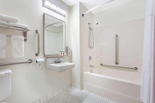 y baño blanco con lavabo y ducha. en Days Inn by Wyndham Austin, en Austin