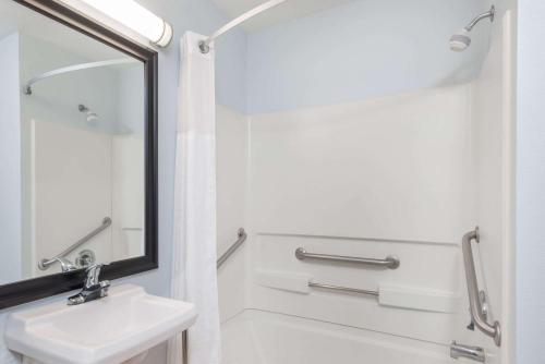 Baño blanco con lavabo y espejo en Days Inn by Wyndham Las Vegas en Las Vegas