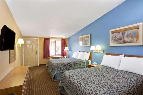 a hotel room with two beds and a flat screen tv at Days Inn by Wyndham Lawrenceville in Lawrenceville