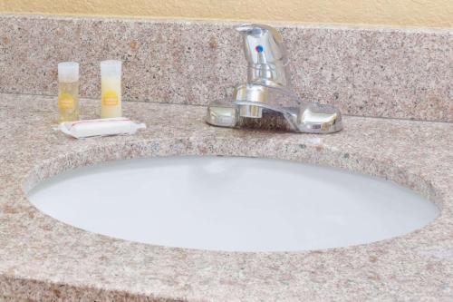 a sink with two glasses of beer on a counter at Days Inn by Wyndham Lawrenceville in Lawrenceville