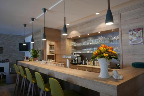 a bar with green chairs and a vase of flowers at Landhotel Salmen in Oberkirch
