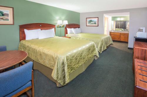 una camera d'albergo con due letti e un tavolo di Days Inn by Wyndham Ontario Airport a Ontario