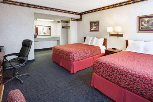 a hotel room with two beds and a desk at Sunset Inn in Costa Mesa