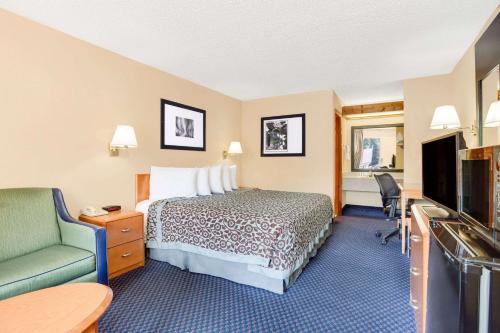 a hotel room with a bed and a green chair at Days Inn by Wyndham Downtown Aiken in Aiken