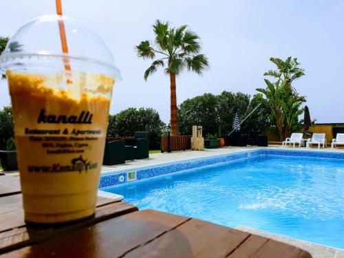 a drink sitting on a table next to a swimming pool at Kanalli Apartments in Pomos