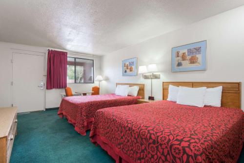 Habitación de hotel con 2 camas con sábanas rojas en Days Inn by Wyndham Gallup en Gallup