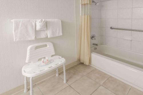 a white bathroom with a white tub and a white stool at Columbus Grand Hotel & Banquet Center in Columbus