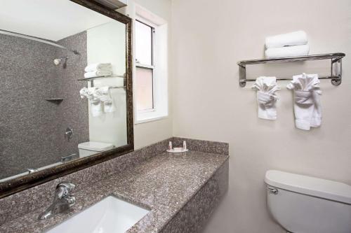 a bathroom with a sink and a mirror and a toilet at Sunset Inn in Costa Mesa