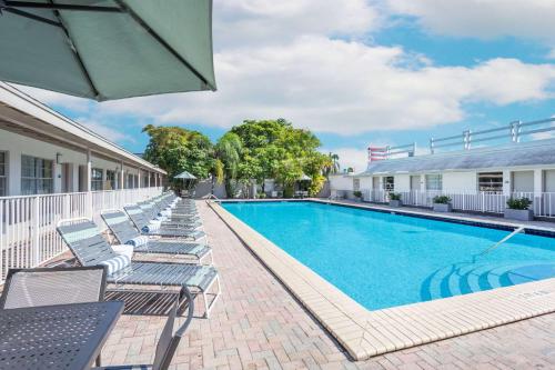 a swimming pool with lounge chairs and an umbrella at Days Inn by Wyndham Miami Airport North in Miami