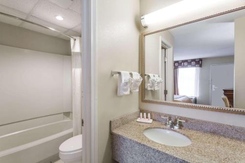 a bathroom with a sink and a toilet and a mirror at Days Inn by Wyndham Orangeburg in Orangeburg