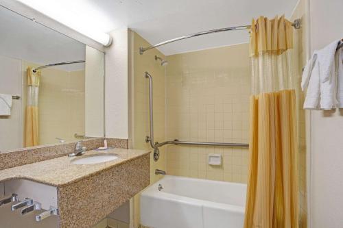 a bathroom with a sink and a tub and a shower at Days Inn by Wyndham Norfolk Military Circle in Norfolk