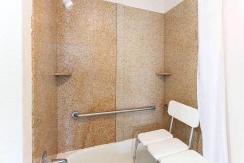 ein Bad mit einer Dusche, einem WC und einem Stuhl in der Unterkunft Days Inn by Wyndham Dahlonega University Area in Dahlonega