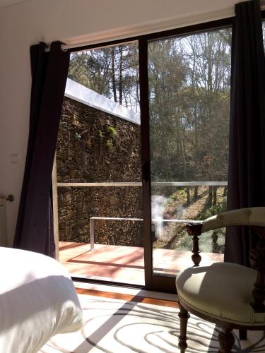 a bedroom with a window and a bed and a chair at Liiiving in Caminha | Oak Tree Chill House in Caminha