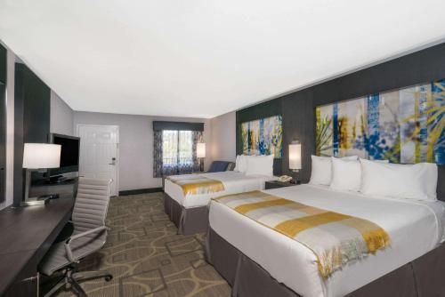 a hotel room with two beds and a desk and a television at Days Inn by Wyndham Asheville Downtown North in Asheville