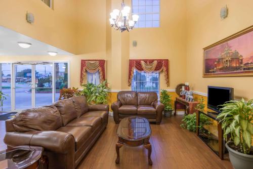 a living room with a leather couch and a table at Days Inn by Wyndham San Antonio Southeast Frost Bank Center in San Antonio