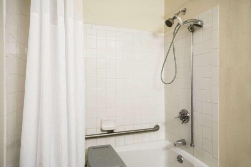 a bathroom with a shower with a white shower curtain at Days Inn by Wyndham Greenwood SC in Greenwood