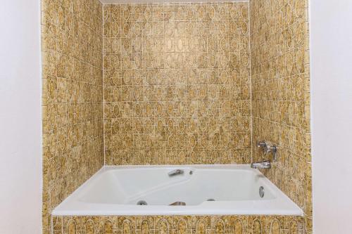 a bath tub in a bathroom with a tiled wall at Days Inn by Wyndham Camarillo - Ventura in Camarillo