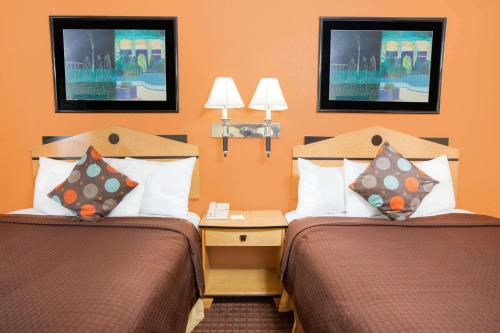 2 camas en una habitación de hotel con paredes de color naranja en Days Inn by Wyndham Alma ARKANSAS, en Alma
