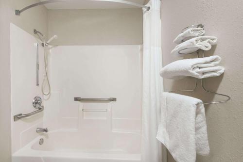 uma casa de banho com chuveiro e toalhas brancas em Days Inn by Wyndham Muncie -Ball State University em Muncie