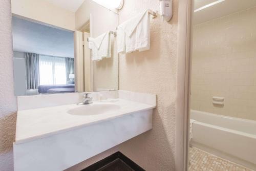 a bathroom with a sink and a mirror and a tub at Days Inn by Wyndham Elizabethtown in Elizabethtown