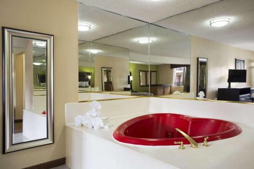 Days Inn by Wyndham Dallas Irving في ايرفينغ: حوض استحمام أحمر في حمام مع مرآة