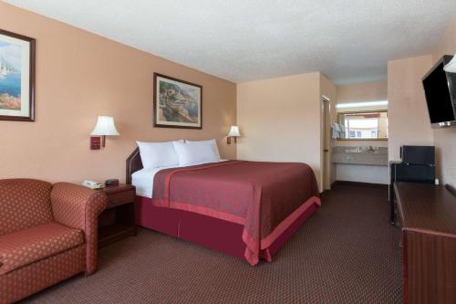 a hotel room with a bed and a chair at Days Inn by Wyndham Waycross in Waycross