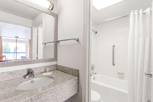 a bathroom with a sink and a shower and a mirror at Days Inn by Wyndham Fredericksburg North in Fredericksburg