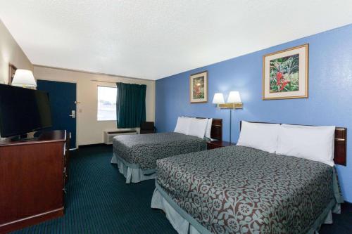 a hotel room with two beds and a flat screen tv at Days Inn by Wyndham Oklahoma City Fairground in Oklahoma City