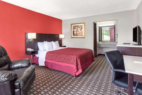 a hotel room with a bed and a couch at Days Inn by Wyndham Cullman in Cullman