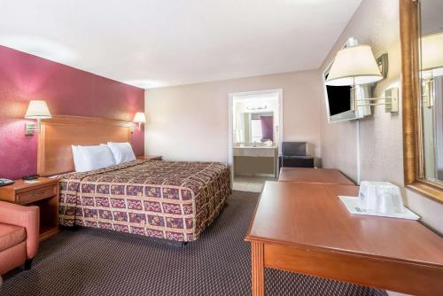 a small hotel room with a bed and a desk at Days Inn by Wyndham San Antonio Splashtown/ATT Center in San Antonio