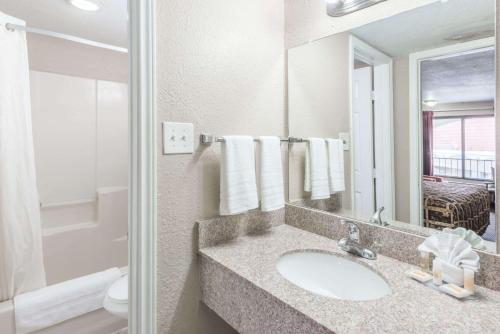 a bathroom with a sink and a toilet and a mirror at Days Inn by Wyndham San Antonio Splashtown/ATT Center in San Antonio