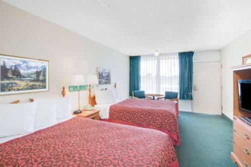 a hotel room with two beds and a flat screen tv at Days Inn by Wyndham Newport in Newport
