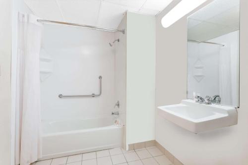 y baño blanco con lavabo y ducha. en Days Inn by Wyndham Augusta Wheeler Road, en Augusta