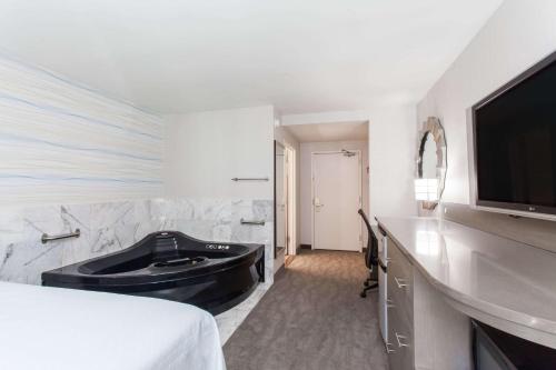 a hotel room with a bath tub and a television at Days Inn by Wyndham Lanham Washington DC in Lanham