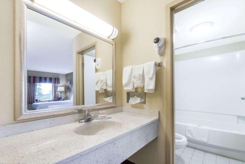 a bathroom with a sink and a mirror and a toilet at Days Inn Lexington SE Hamburg in Lexington