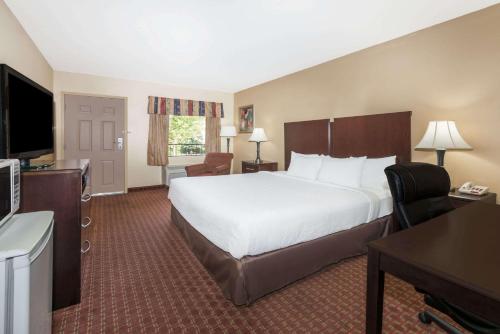 een hotelkamer met een groot bed en een bureau bij Days Inn by Wyndham Lexington Southeast in Lexington