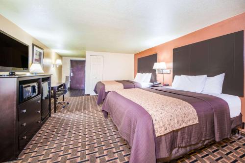 a hotel room with two beds and a flat screen tv at Days Inn by Wyndham Joplin in Joplin