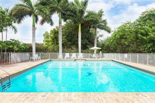 a swimming pool with palm trees and a fence at Days Inn by Wyndham Fort Lauderdale-Oakland Park Airport N in Fort Lauderdale