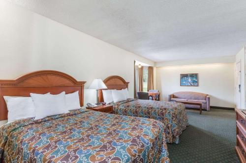 una habitación de hotel con 2 camas y una silla en Days Inn by Wyndham Petersburg/South Fort Lee, en Petersburg