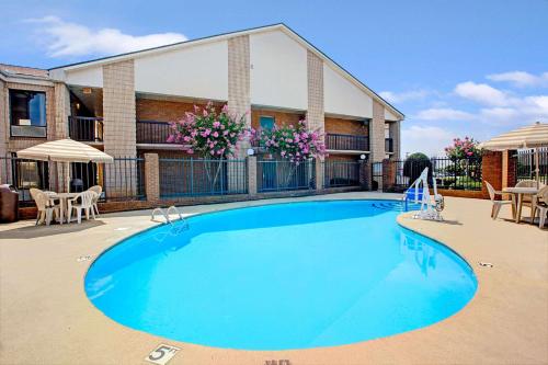 a swimming pool with chairs and a building at Days Inn by Wyndham Mooresville Lake Norman in Mooresville